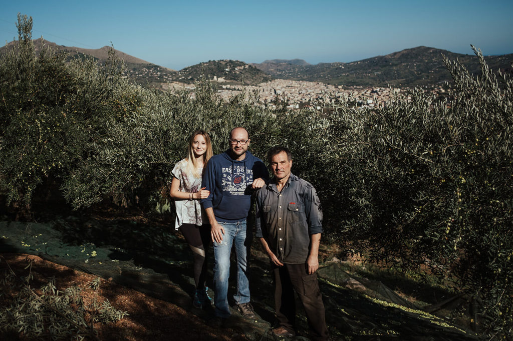 Familie D'Assisi steht im Olivenhain, dahinter die Stadt Misilmeri