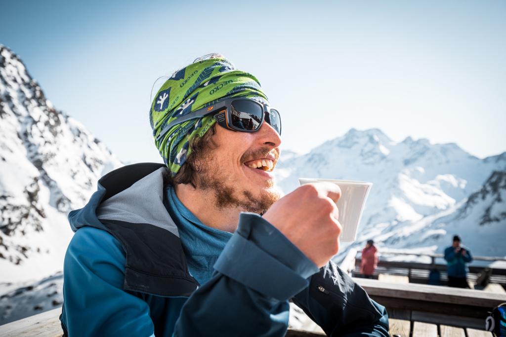 Ein Mann genießt eine Tasse Tee auf der Terrasse einer Schutzhütte
