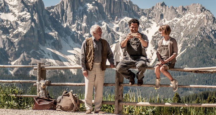 Drei Menschen sitzen auf einem Zaun vor den Südtiroler Dolomiten - 10 Dinge über Südtirol